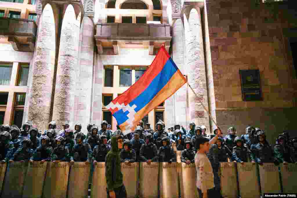 Young protesters wave the flag of the separatist Nagorno-Karabakh region in front of riot police guarding Armenia&rsquo;s government building in Yerevan on September 22.