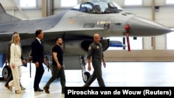 Președintele ucrainean Volodimir Zelenski și șeful NATO, Mark Rutte, lângă un avion F-16 în Eindhoven, Olanda, august 2023.