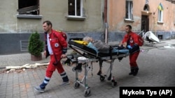 An elderly woman is carried on a stretcher by emergency service workers after a Russian missile attack on an apartment building in Lviv on July 6.