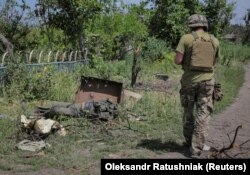 Український військовий проходить повз тіло російського військового у Нескучному, 13 червня 2023 року