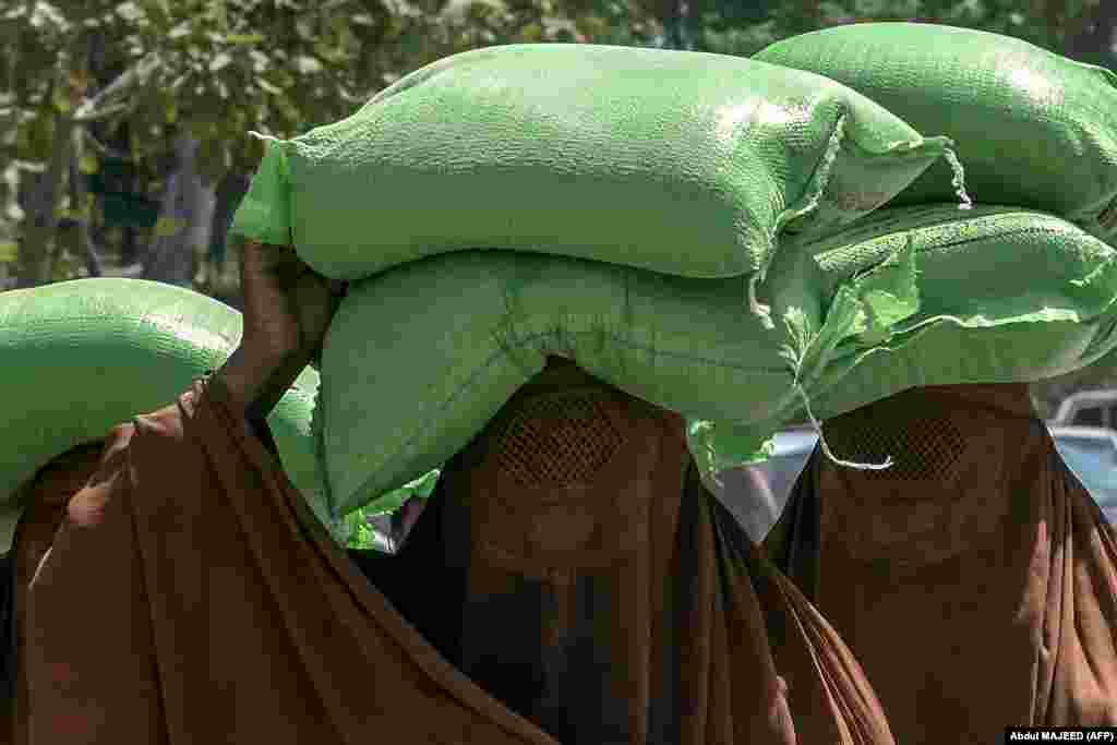 Burqa-clad women leave after collecting free bags of flour from a government distribution point in Peshawar, Pakistan.