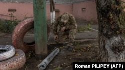 A man inspects part of a missile that fell next to a residential building that was damaged during an overnight Russian attack in the southern city of Kherson on October 30.