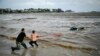 Două persoane încearcă să scoată afară o maşină cuprinsă de ape în zona campingulului Arapia din oraşul-staţiune Tsarevo, de pe coasta de sud a Mării Negre din Bulgaria.