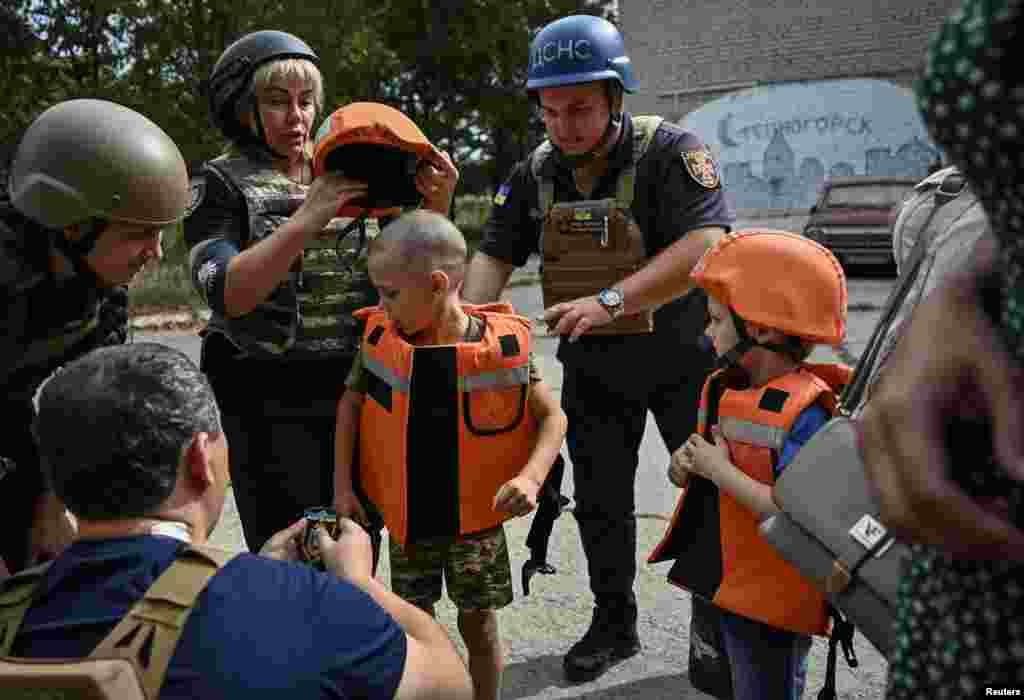 Police officers put body armor on children before their evacuation from a village near the front line in war-wracked Ukraine.&nbsp;