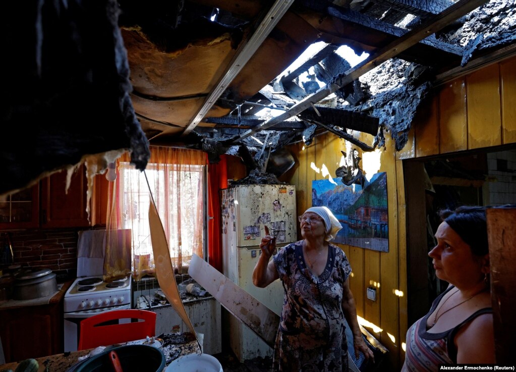 Banorja vendase Olha Paramonova, 49 vjeçe, dhe nëna e saj, Natalya, shikojnë çatinë e shkatërruar të shtëpisë së tyre, të dëmtuar nga bombardimet e fundit, në Donjeckun e kontrolluar nga Rusia.