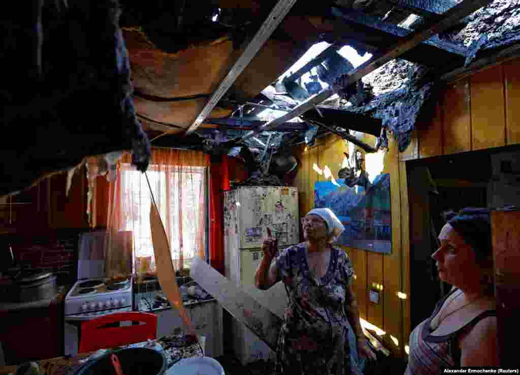 Local resident Olha Paramonova, 49, and her mother, Natalya, look at the destroyed roof of their house, damaged by recent shelling, in Russia-controlled Donetsk.