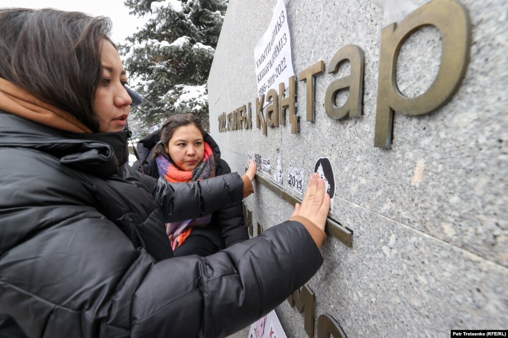 Активистки гражданского движения Oyan, Qazaqstan наклеивают стикеры, посвящённые жертвам Январских событий, на мемориал «Тағзым»