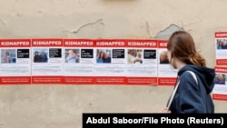 Женщина смотрит на плакаты с изображением пропавших без вести граждан Израиля, вероятно находящихся среди заложников, удерживаемых в секторе Газа