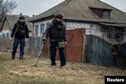 Sappers inspect an area for mines and unexploded shells in Kharkiv region.