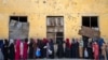 Afghan women wait to receive food rations distributed by a humanitarian aid group in Kabul.