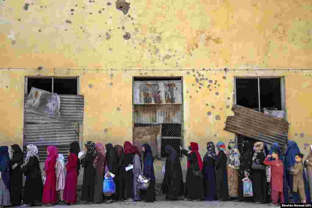 Afghan women wait to receive food rations distributed by a humanitarian aid group in Kabul.