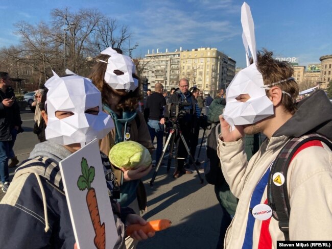 Të rinjtë, me maska lepuri dhe lakra, jashtë ndërtesës së Kuvendit në Beograd.
