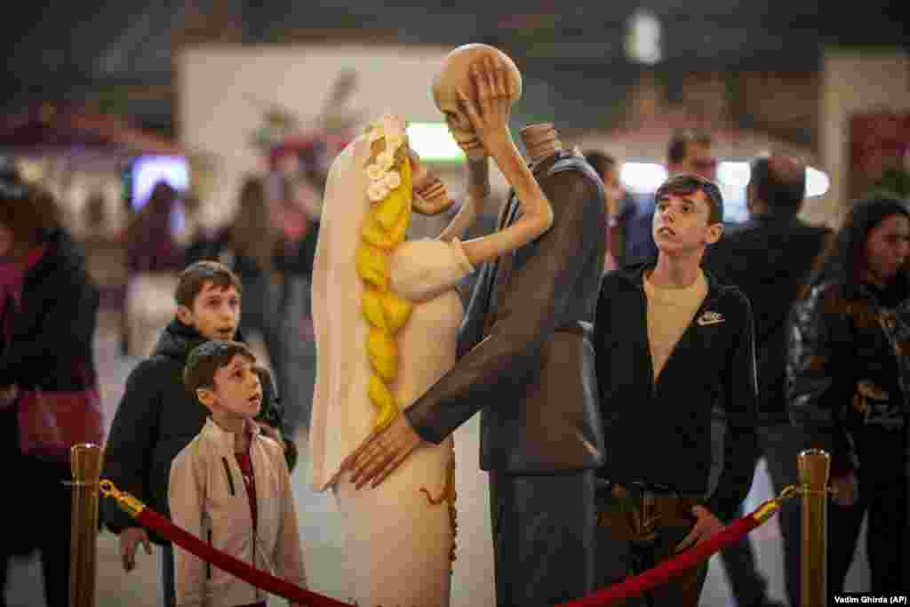 People look at a skeleton couple kissing as part of an installation titled &#39;Till Death Do Us Part during a Valentine&#39;s Day event in Bucharest.