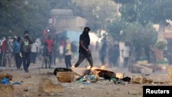 Pristalica senegalskog opozicionog lidera Osmana Sonka hoda pored zapaljene barikade tokom sukoba sa snagama bezbjednosti, Dakar, 3. jun 2023.