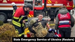 Рятувальники надають допомогу постраждалому колезі на місці російського ракетного удару під час атаки Росії на Україну, Одеса, Україна, 15 березня 2024 року
