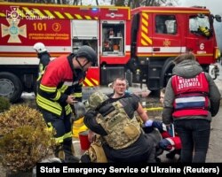 Рятувальники надають допомогу постраждалому колезі на місці російського ракетного удару під час атаки Росії на Україну, Одеса, Україна, 15 березня 2024 року.