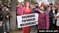 A woman slaps a cardboard cutout of Moldova's pro-Western President Maia Sandu, with a placard reading "Enemy of the Moldovan People," during a protest initiated by the populist Shor party, in Chisinau on November 13.