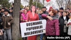 Një grua godet figurën e presidentes moldave, Maia Sandu, të krijuar nga kartoni. Në pankartën e vendosur shkruan "armike e populit të Moldavisë". Kishiniev, 13 nëntor 2022.