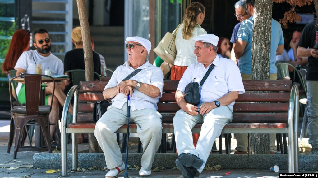Dy të moshuar duke pushuar nën hijen e pemëve në sheshin e kryeqytetit. 18 korrik 2023.