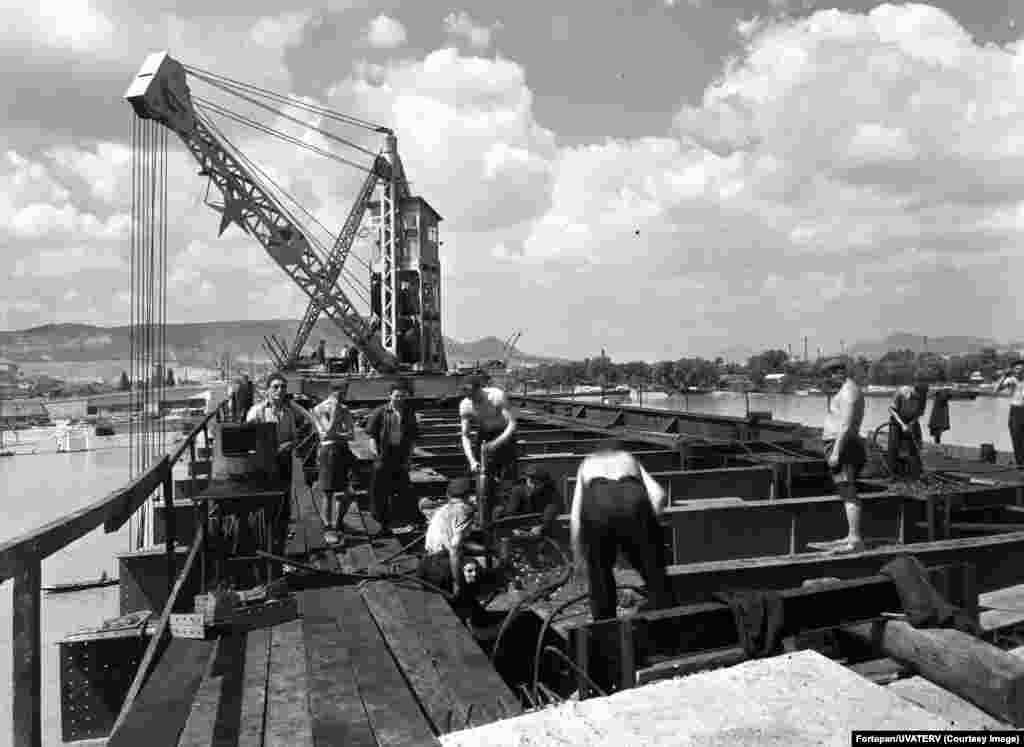Workers rebuilding a bridge over the Danube in 1950 toiled under both the summer sun and a communist red star (top left). &nbsp;
