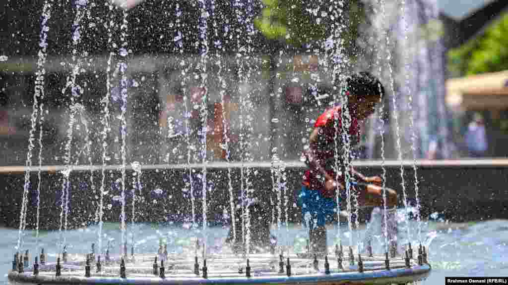 Dete se rashlađuje u fontani u glavnom gradu Kosova, 18. jula 2023. godine