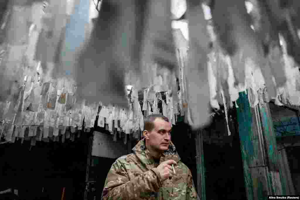 A Ukrainian soldier smokes under camouflage nets near the front line in the Donetsk region. (file photo)