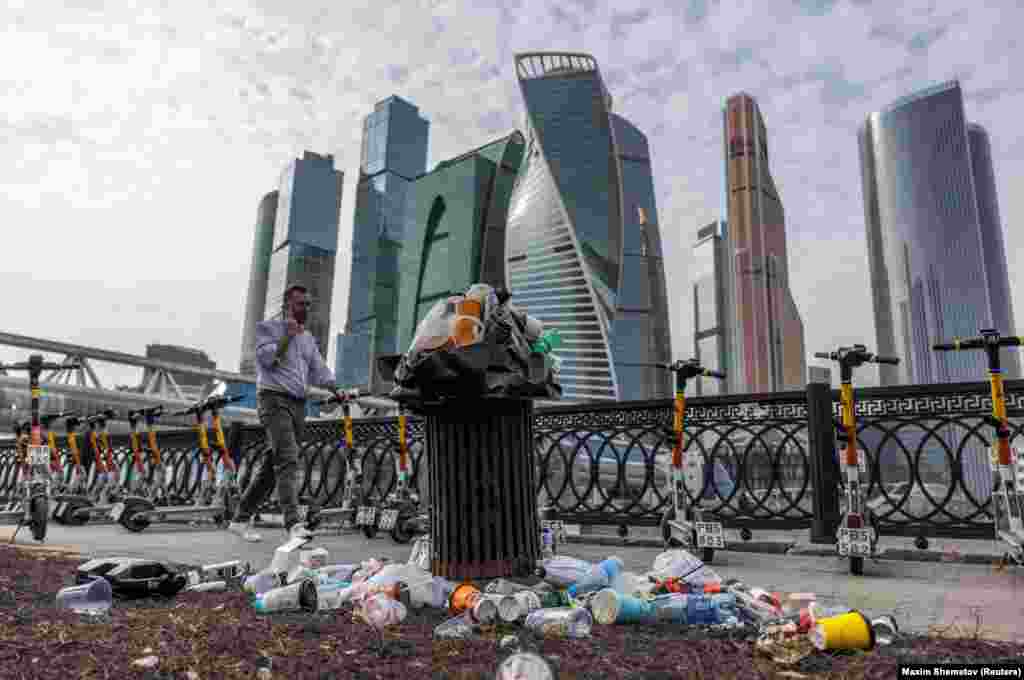 A man walks past an overflowing trash can next to skyscrapers of Moscow&#39;s International Business District, also known as Moskva-City.