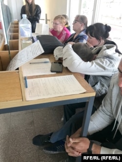 People filling out forms inside the Russian border post.