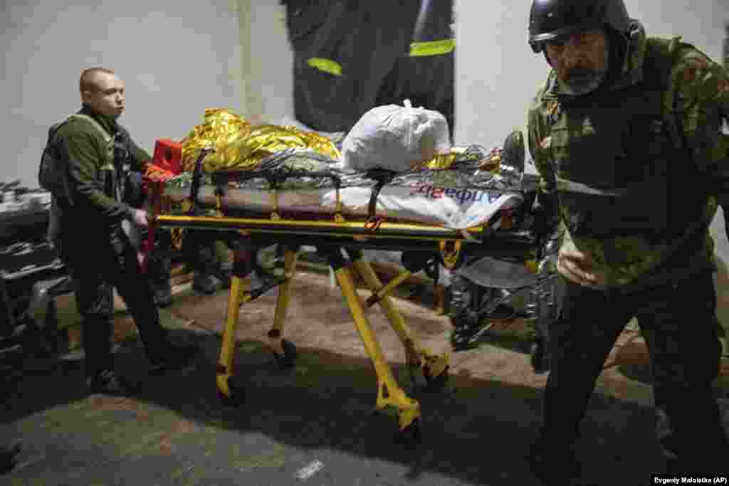 Mjekët ushtarakë ukrainas bartin me një barelë një të plagosur që arrin nga fusha e betejës në një spital fushor pranë Bahmut, Ukrainë, të dielën më 26 shkurt 2023.