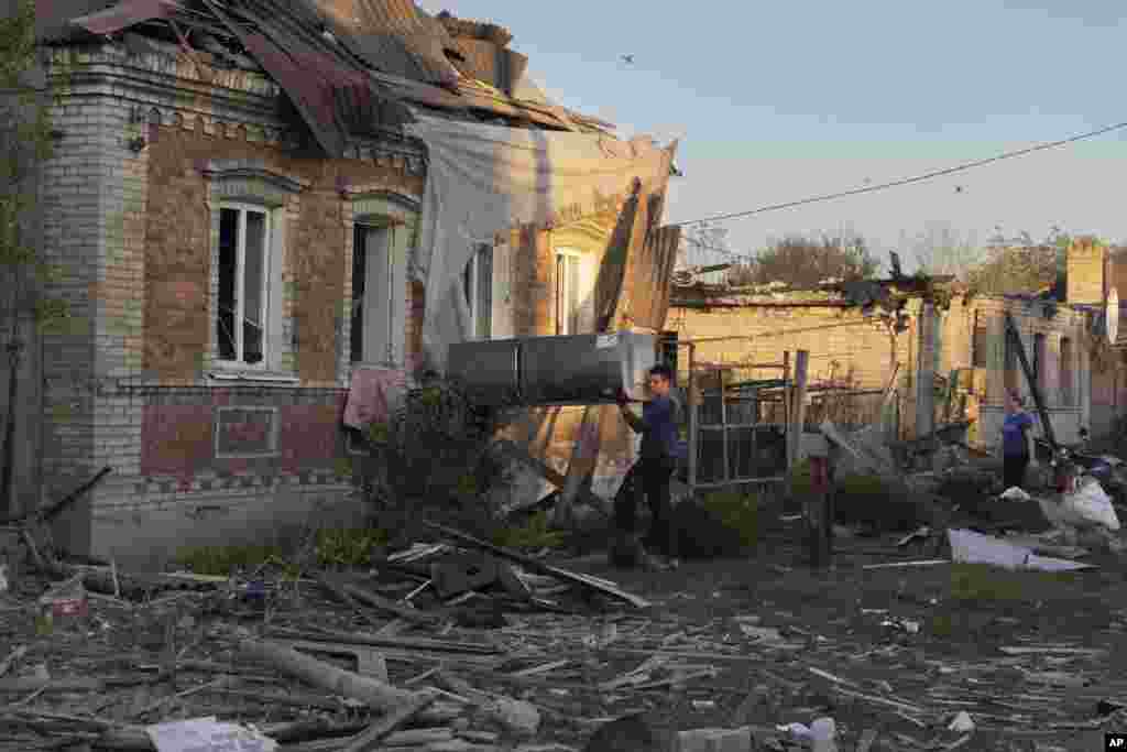 Місцеві жителі переносять холодильник з будинку, пошкодженого внаслідок російського ракетного обстрілу, в Костянтинівці, Донецька область, 27 вересня 2023 року.