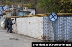 Workers cut down a fence made from Azerbaijani license plates.
