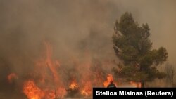 Пожарникар гаси пожар во близина на селото Кандили, во близина на Атина, Грција, 19 јули 2023 година