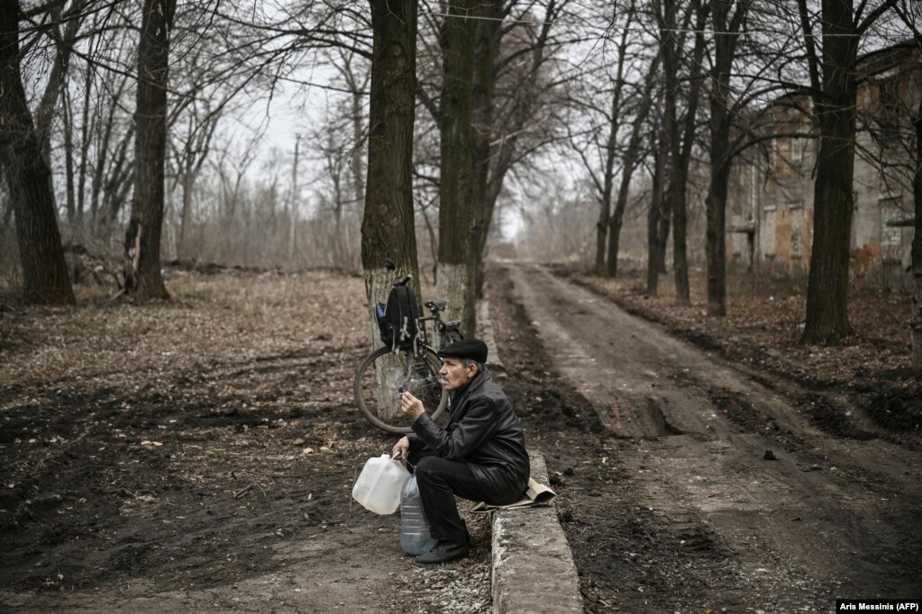 Një burrë i moshuar tymos një cigare ndërsa pret të mbushë enët me ujë në Chasiv Yar pranë vijës së frontit në Ukrainën lindore.