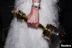 Мишел Йео "Оскар" статуэткасын көтөрүп баратат.