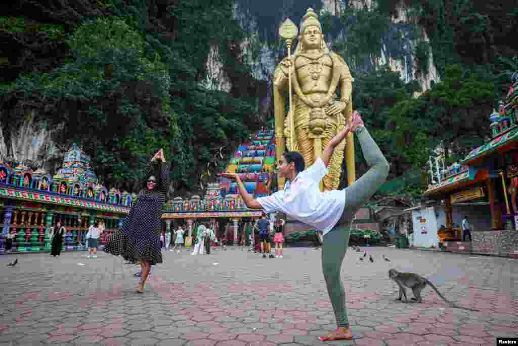 Žene izvode jogu ispred statue hinduističkog boga Murugana na 10. Međunarodni dan joge u pećinama Batu, Malezija, 21. juna 2024.