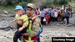 Troops help residents escape flooding and mudslides in the Mount Abshir Ata area of the Osh region insouthern Kyrgyzstan on June 29.