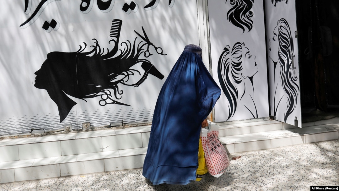 An Afghan woman walks past a beauty salon in Kabul.