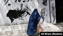An Afghan woman walks past a beauty salon in Kabul.