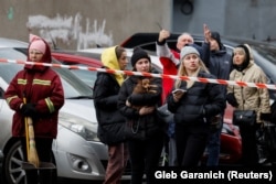 Кияни дивляться на результат влучення російської ракети в цивільний об'єкт у Києві. Україна, 9 березня 2023 року