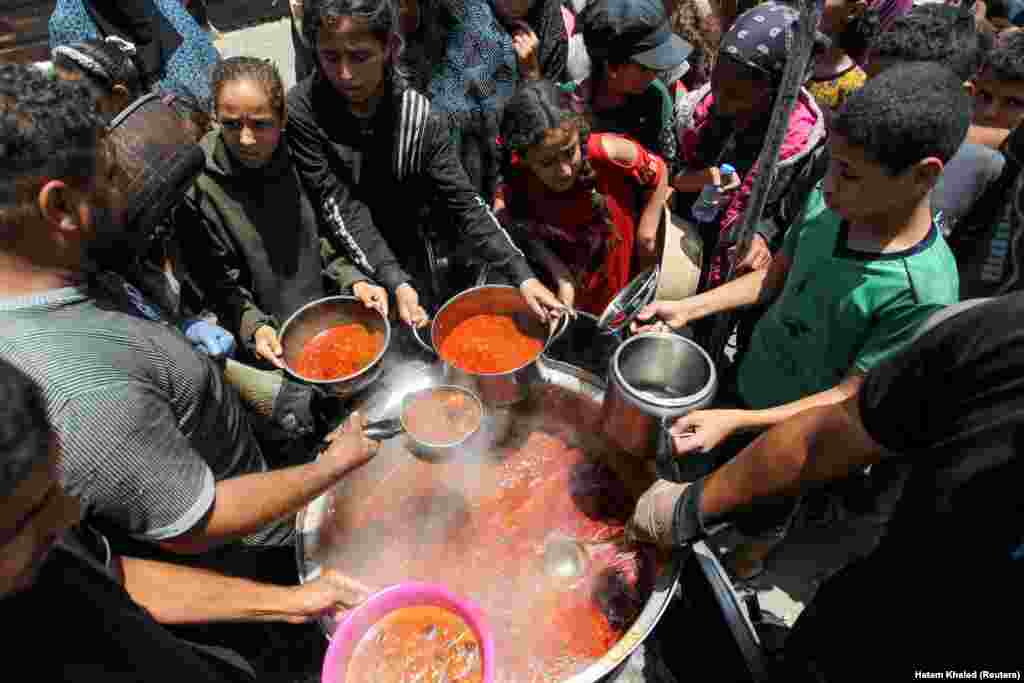 Palestinezët e mbledhur për të marrë ushqim të gatuar nga një kuzhinë bamirësie, mes mungesës së theksuar të ushqimit dhe furnizimeve me ndihma, derisa po vazhdon konflikti ndërmjet Izraelit dhe Hamasit - i shpallur organizatë terroriste nga Shtetet e Bashkuara të Amerikës dhe Bashkimi Evropian. Fotografia është bërë në Han Junis, në pjesën jugore të Rripit të Gazës më 19 qershor 2024.