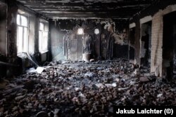 The same schoolroom as photographed above, strewn with burned cans of food, seen in March 2023.