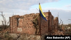 A Ukrainian soldier raises his country's flag over the frontline village of Andriyivka in the Donetsk region on September 16. 