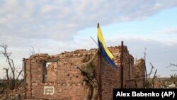 Un soldat ucrainean arborează drapelul țării pe o clădire din Klișciivka 