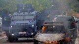 Pjesëtarët e forcave speciale të Policisë qëndrojnë pranë një makine të djegur, pas përleshjeve mes PK-së dhe protestuesve serbë në Zveçan.<br />
&nbsp;