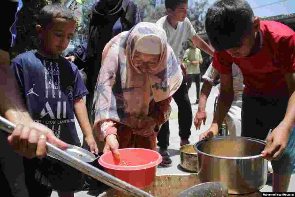 Palestinezët duke marrë ushqimin e gatuar nga një kuzhinë bamirësie, ndërsa po përballen me mungesën e ushqimit dhe gjërave tjera elementare për jetesë në kampin e refugjatëve Xhabalia, në veri të Rripit të Gazës, 19 qershor 2024.