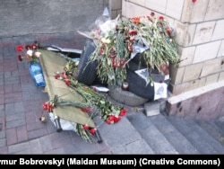 Люди роками приносять квіти і лампадки до постріляного фасаду готелю «Україна»