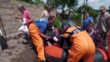 Ukrainian rescuers help pull local residents from a boat during an evacuation from a flooded area