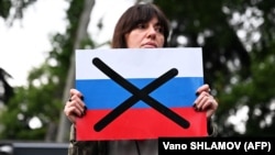 Участница протестов держит перечёркнутый флаг России во время митинга против спорного законопроекта об «иностранном влиянии». Тбилиси, 3 мая 2024 года