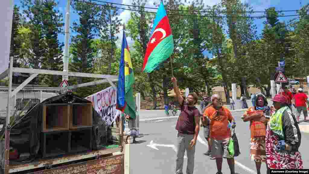 Demonstranti u Noumei u Novoj Kaledoniji mašu azerbejdžanskom zastavom. Ova slika iz januara 2024. jedna je od nekoliko na kojima se vide zastave i simboli daleke kavkaske zemlje koju nosi pripadnik domorodačkog naroda Kanaka uoči masovnih nemira koji trenutno potresaju Novu Kaledoniju. &nbsp;