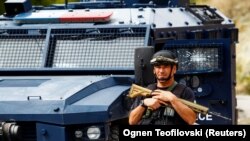 Një zyrtar policor duke qëndruar pranë automjetit të dëmtuar të Policisë së Kosovës, pas sulmit të 24 shtatorit 2023 nga një grup i armatosur në fshatin e veriut të Kosovës, Banjskë.